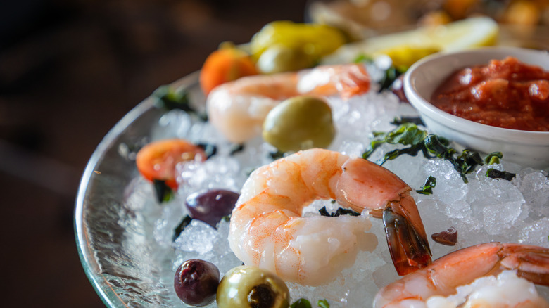 Fine dining-style shrimp cocktail on ice with dipping sauce on the side