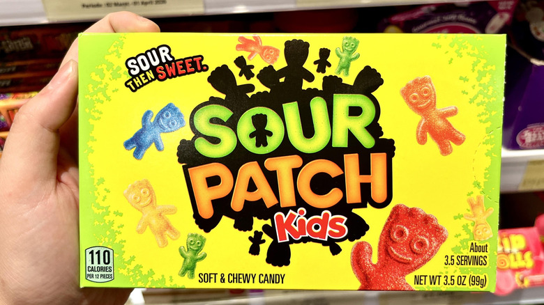 A hand holds a box of Sour Patch Kids