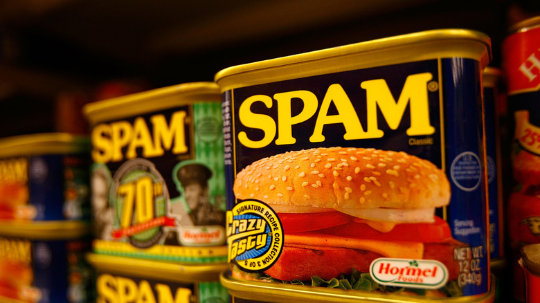 Cans of Spam meat stacked on grocery store shelf.