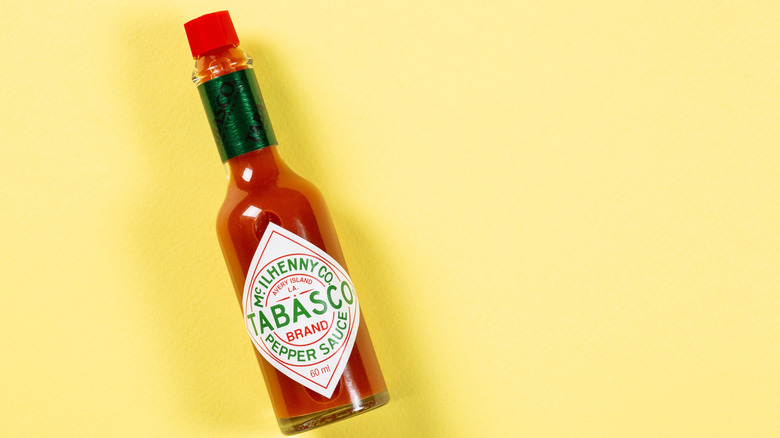 bottle of Tabasco sauce lying on its side on a yellow countertop