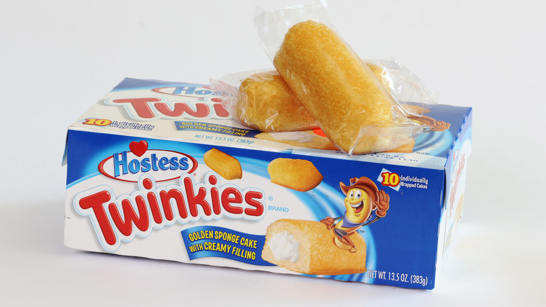 Two packaged Twinkies resting on top of a box of Twinkies