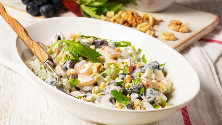 Chopped and dressed Waldorf salad in bowl with wood-handled fork.