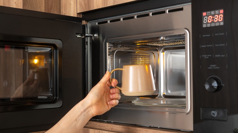 putting mug into black microwave