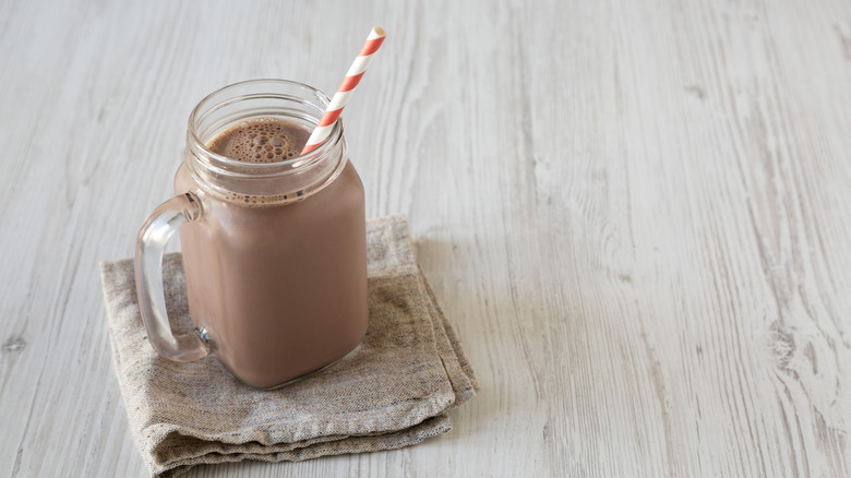 A glass of chocolate milk and a straw