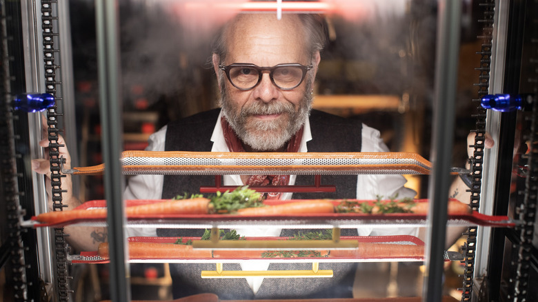 Alton Brown is looking at carrots in some sort of heating element.