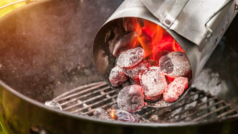 Pouring flaming hot charcoal onto a grill