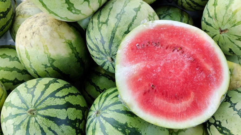 Whole and halved watermelons sitting in a pile