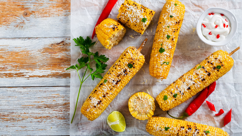 Grilled corn on the cob with fresh red chile pepper, parsley, and grated cheese