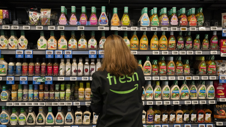 An Amazon Fresh employee standing in front of the salad dressing aisle