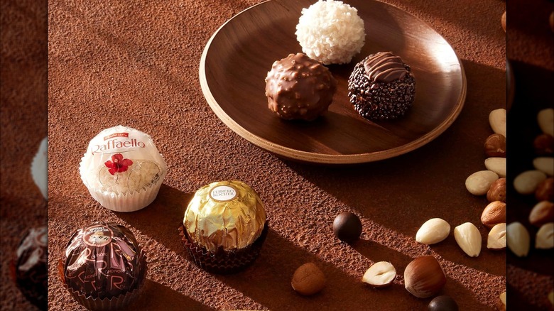 Three types of Ferrero Rocher chocolates in wrapper and unwrapped in wood bowl