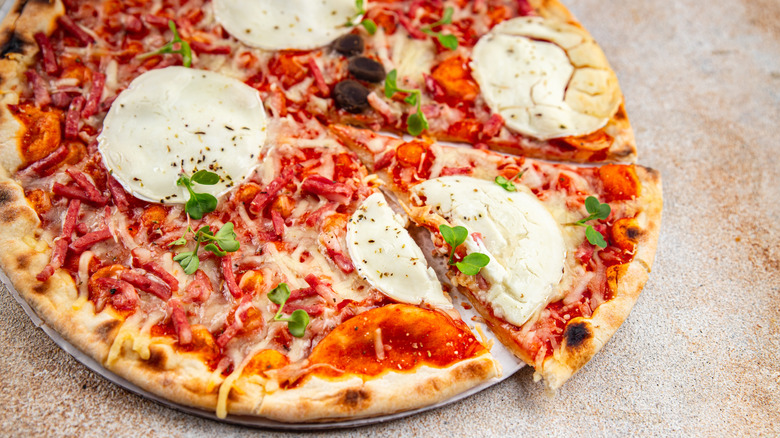 Pizza with goat cheese, tomato sauce, and strips of bacon