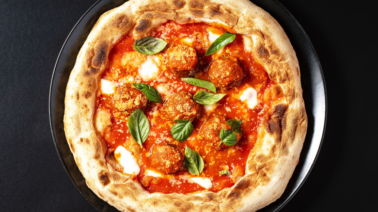 Pizza with meatballs on black background