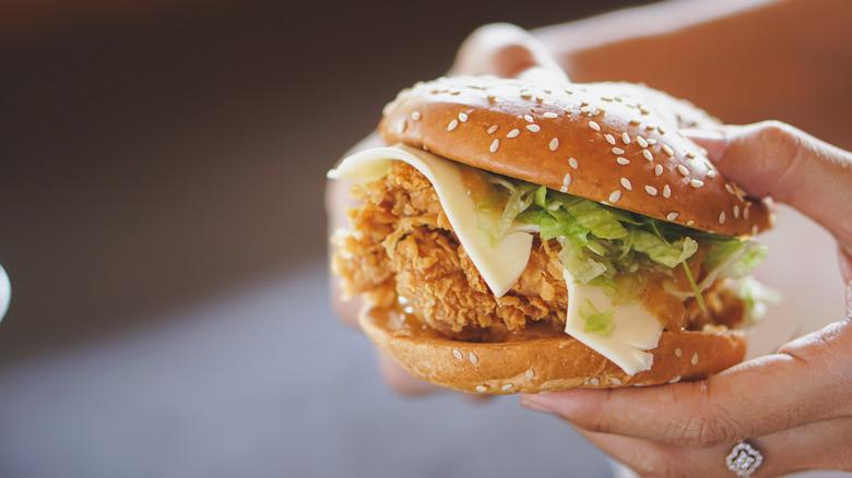 hands holding fried chicken sandwich