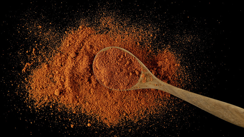 Taco seasonings with a wooden spoon on a black background