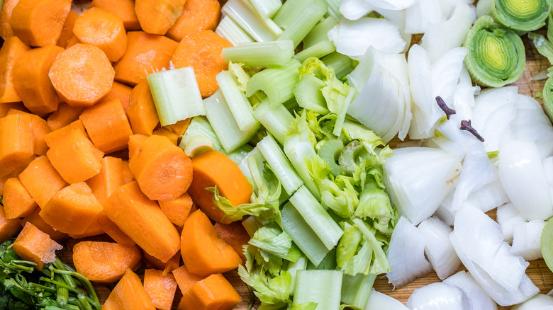 Chopped vegetables such as carrots and celery on a wooden cutting board