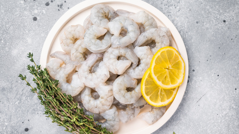 A plate of raw shrimp with lemon and parsley