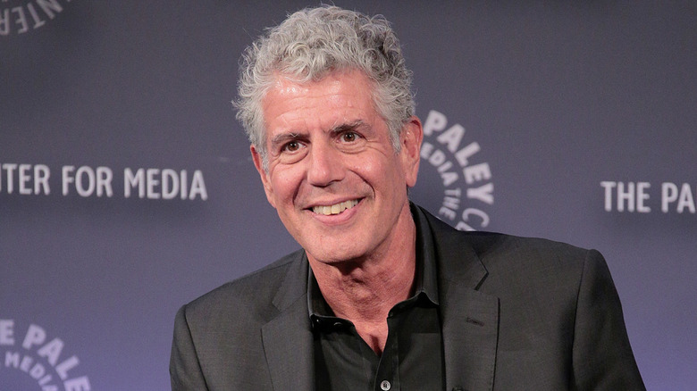 Anthony Bourdain smiling while sitting at a public event