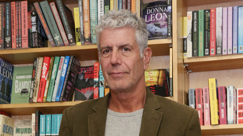 Anthony Bourdain in front of bookshelf