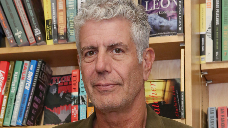 Anthony Bourdain in front of bookshelf
