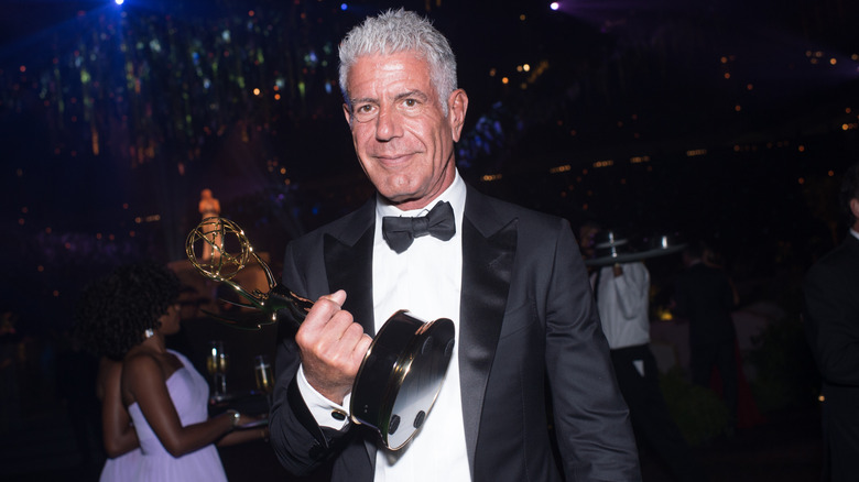 Anthony Bourdain holding his Emmy Award inside the darkened Emmy venue in 2014