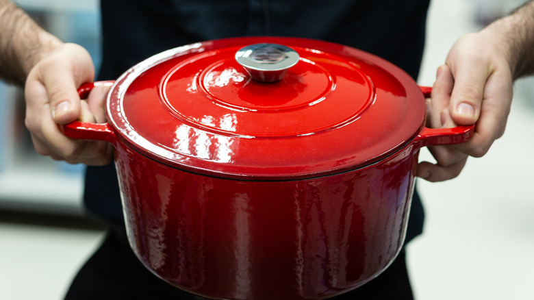 a person holding a dutch oven.