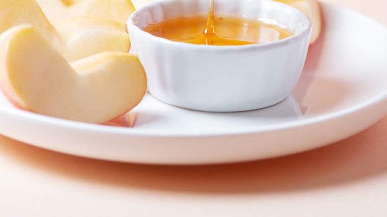 Apple slice being dipped in honey