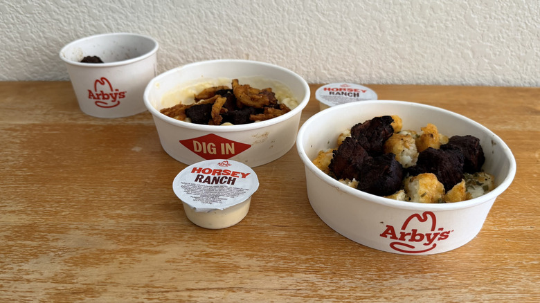 Arby's Steak 'n Mac Bowl, Steak 'n Potato Bowl, and Steak Nuggets with Horsey Ranch Sauce in a diagonal row