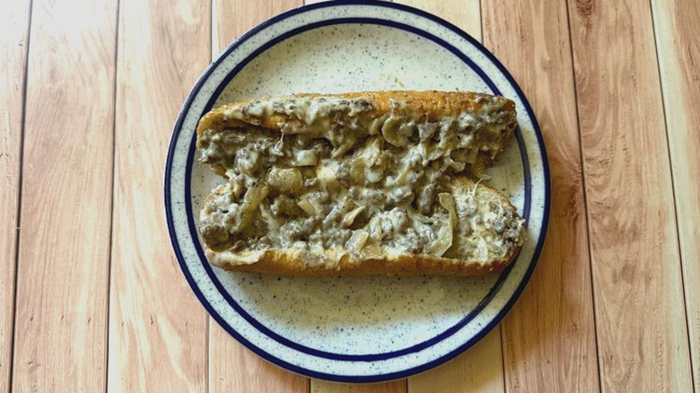Arby's Angus Cheesesteak open on plate to show gooey meat, veggie, and cheese innards