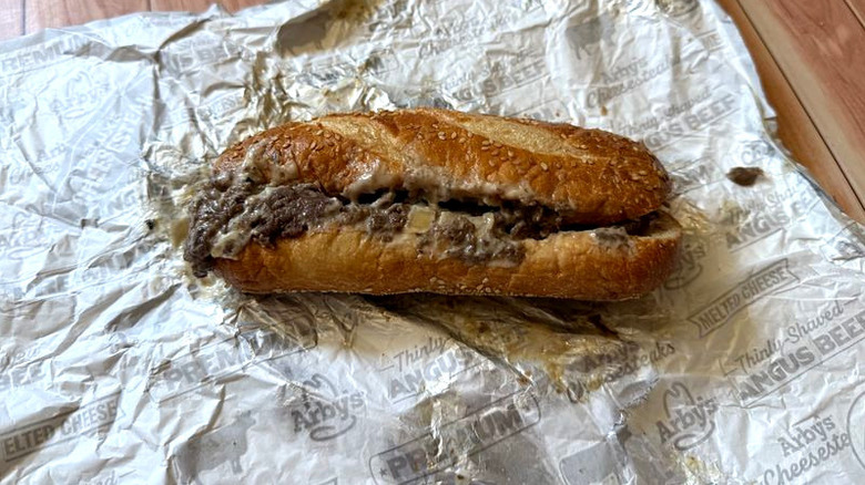 Arby's Angus Cheesesteak sandwich sits on foil wrapper