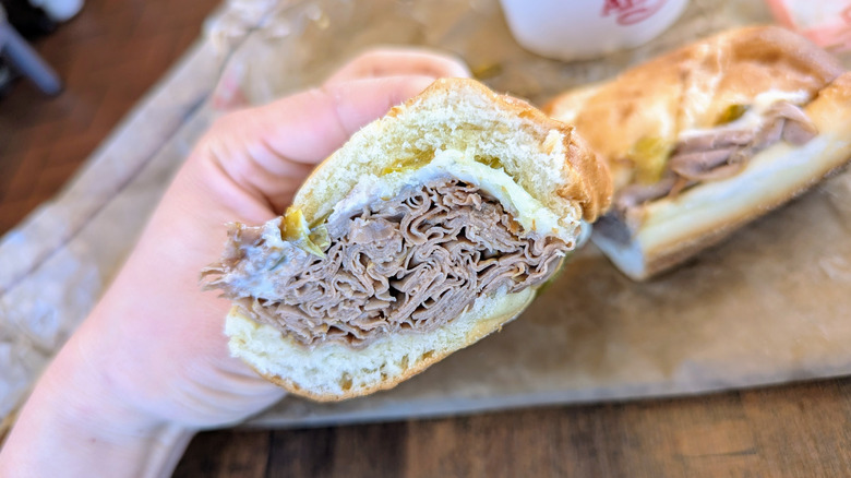 hand holding italian beef dip sandwich