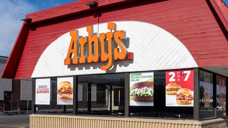 The exterior of an Arby's location with the word "Arby's" in orange letters on the building.
