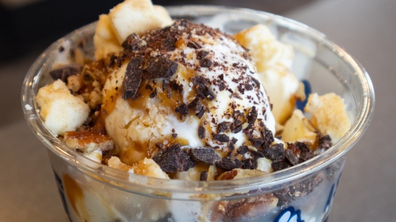 A cup of Culver's frozen vanilla custard topped with chocolate shavings and caramel syrup