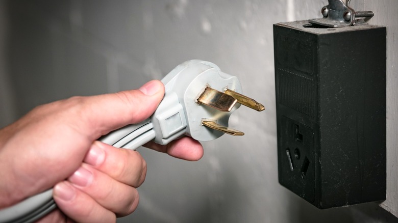 A three-prong power cord for 240-volt outlet held in hand.