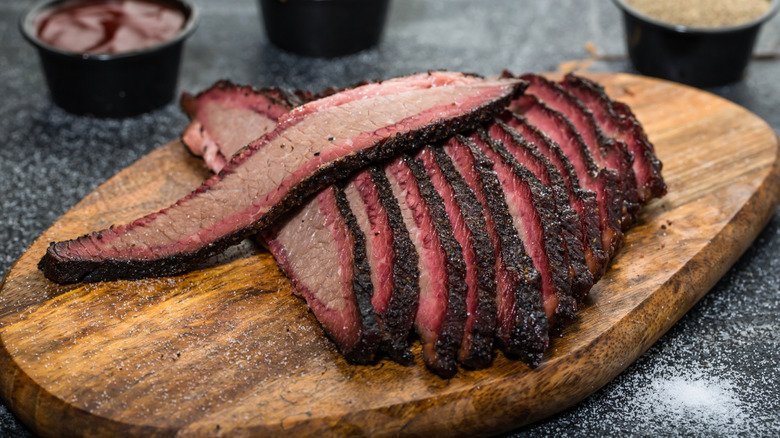 Several pieces of sliced brisket on a wooden serving board