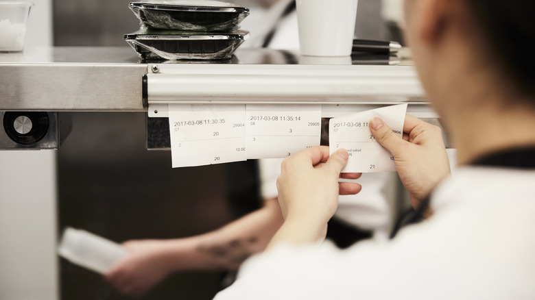 A restaurant worker removing an order ticket.