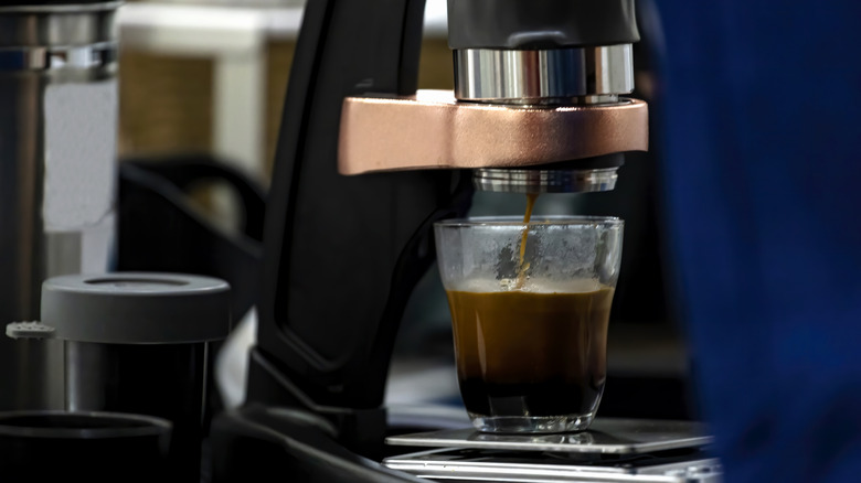 An espresso machine makes espresso into a small glass