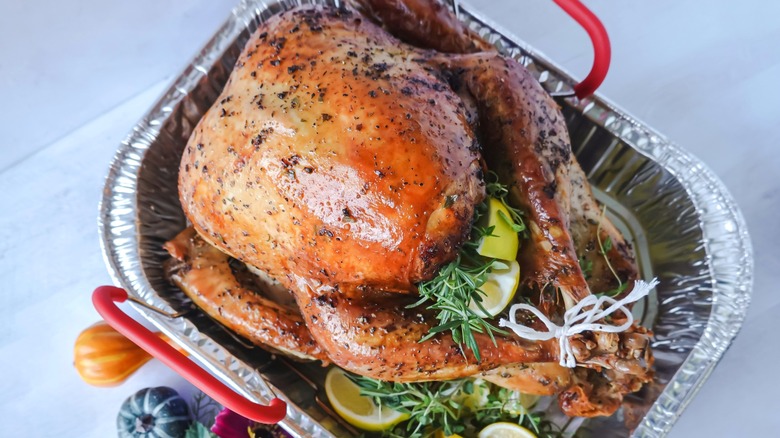 Roasted turkey in foil tray with lemons and herbs