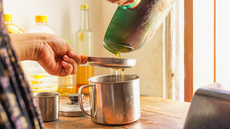 Person pouring oil into a strainer