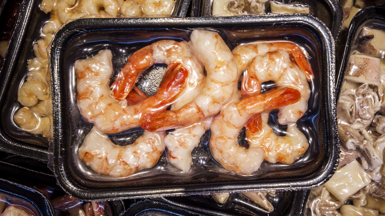 Tail-on shrimp vacuum-sealed on a black tray for sous vide cooking