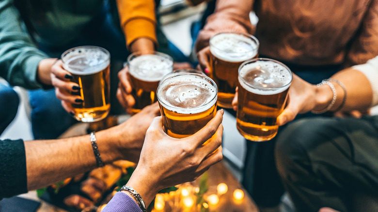 Five arms cheersing their glasses of beer in a circle.