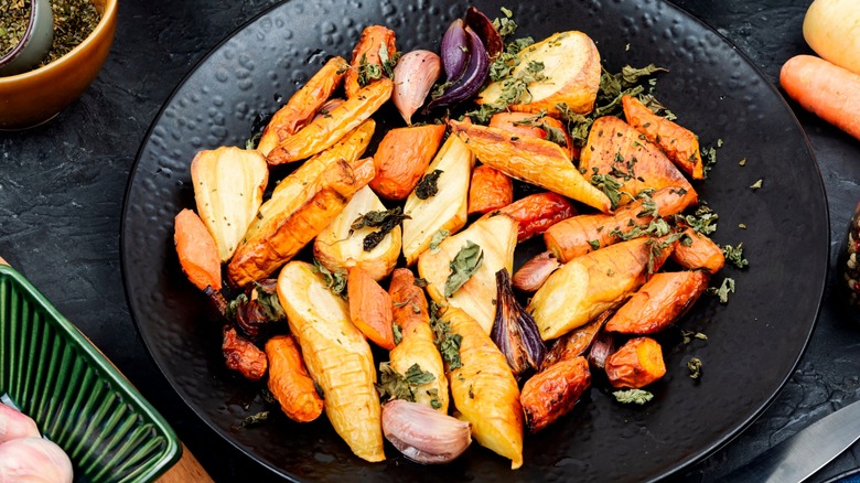 Roasted root vegetables on black plate