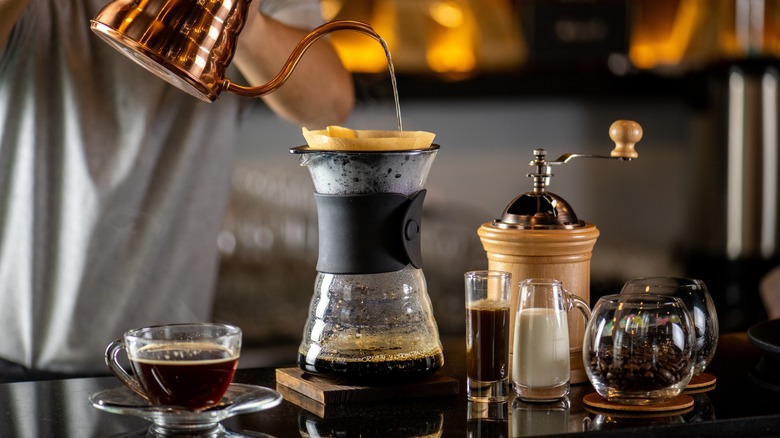 hand pouring water into paper coffee filter