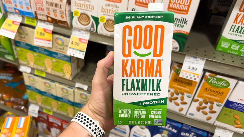 hand holding out Good Karma Flax Milk unsweetened
