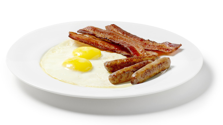 A plate with bacon, sausage, and eggs