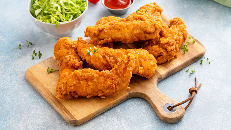 Fried chicken tenders on a wooden board