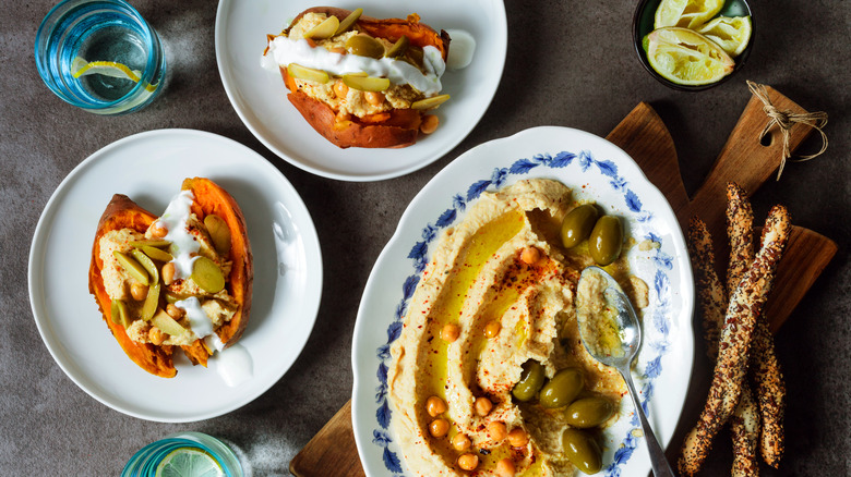Two sweet potatoes filled with hummus and olives plus a plate of hummus and olives
