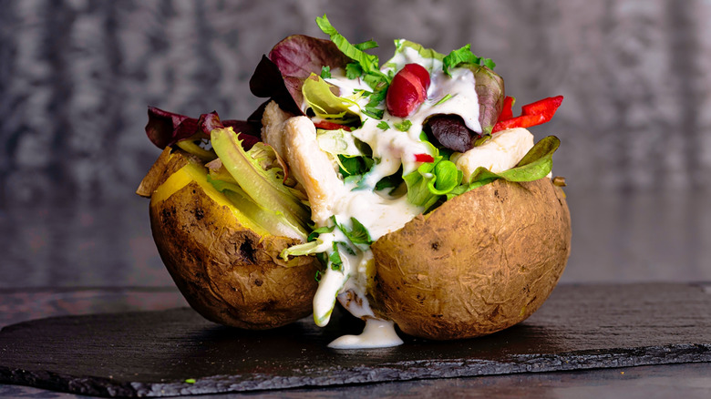 A baked potato loaded with different colorful toppings and vegetables