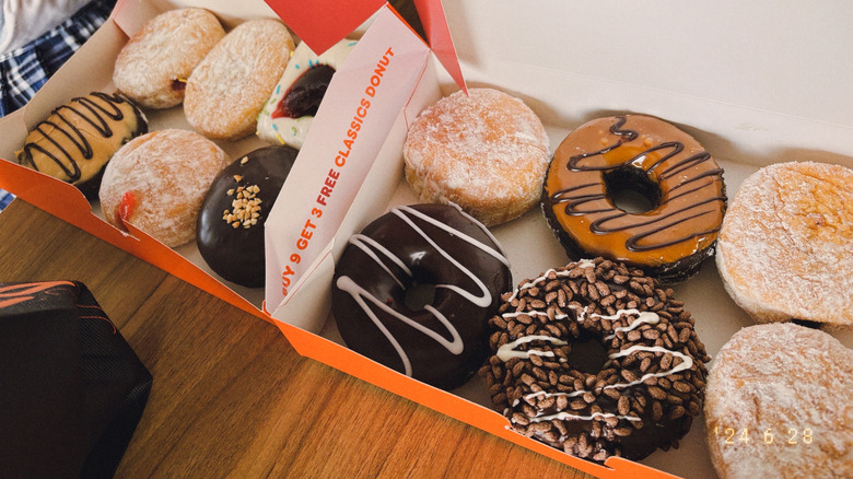 Variety of sugar, plain, and chocolate dunkin donuts in two carryout boxes
