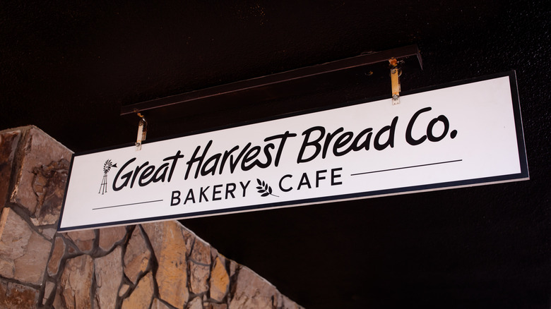 Great Harvest Bread Co. Bakery sign hanging outside store with stone wall