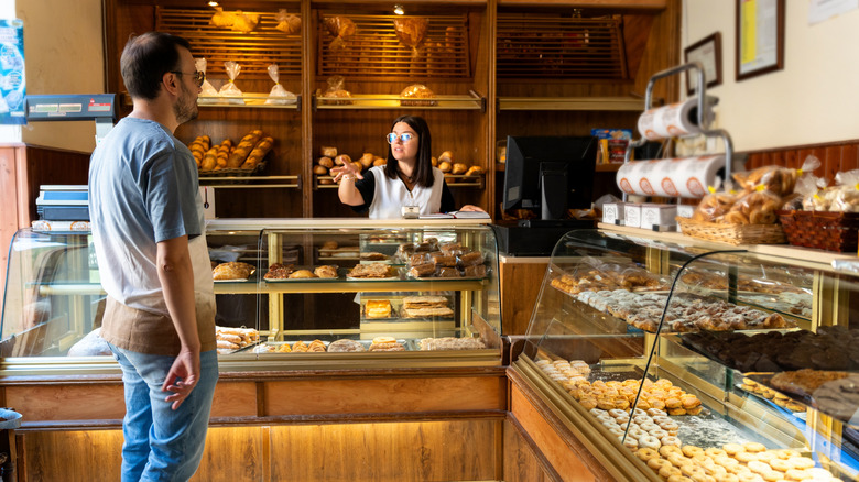 man waiting at counter of bake shop